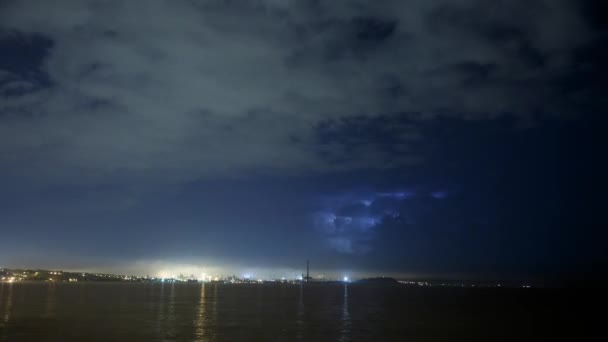 フローティングの雲とパイプから煙で大規模な工業都市スカイラインの上の雷雨のタイムラプスで暗い雰囲気。雷は、夜、海や湖の上点滅します。生態学的な問題の概念. — ストック動画