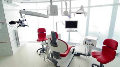 Beyaz diş hekimi ofisi. Lüks minimalist diş kliniği iç cam duvarlar üzerinde diş lamba kırmızı sandalye ve araçları. Ameliyat odası modern donatımın tam çalışma diş hekimliği. Yavaş yavaş hareketli kamera