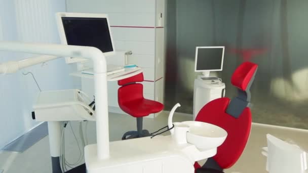 Oficina del dentista blanco. Interior de la clínica dental minimalista de lujo con silla roja y herramientas, lámpara dental sobre paredes de vidrio. Sala de cirugía de odontología llena de equipos modernos. Cámara moviéndose lentamente — Vídeos de Stock