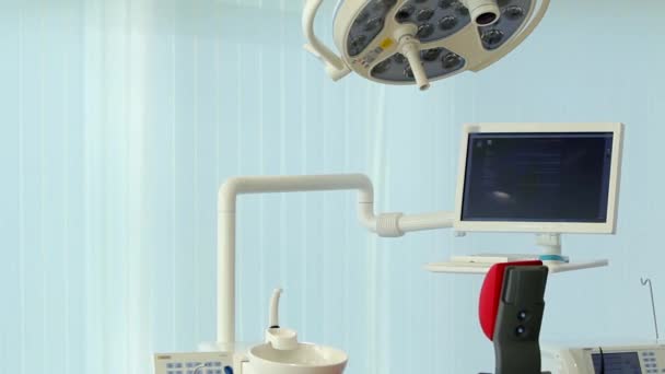 White dentist office. Luxury minimalistic dental clinic interior with red chair and tools, dental lamp over glass walls. Dentistry operating surgery room full of modern equipment. Camera slowly moving — Stock Video