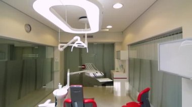 Beyaz diş hekimi ofisi. Lüks minimalist diş kliniği iç cam duvarlar üzerinde diş lamba kırmızı sandalye ve araçları. Ameliyat odası modern donatımın tam çalışma diş hekimliği. Yavaş yavaş hareketli kamera
