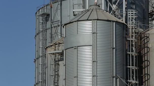 Modern grain terminal. Metal tanks of elevator. Grain-drying complex construction. Commercial grain or seed silos at seaport. Steel storage for agricultural harvest. Clouds floating in sky. — Stock Video