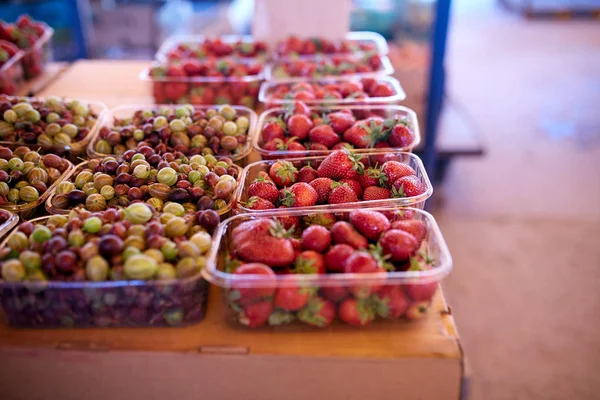 Gooseberry and strawberry on a farm market in the city. Fruits and vegetables at a farmers summer market. — Stock Photo, Image