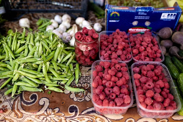 Raspberries, garlic and peas on a farm market in the city. Fruits and vegetables at a farmers summer market. — Stock Photo, Image