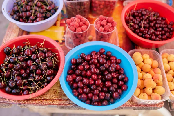 Sweet cherry, raspbeery and apricot on a farm market in the city. Fruits and vegetables at a farmers market. Cherries in boxes and trays — Stock Photo, Image