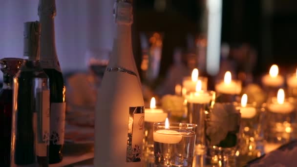 Détails intérieurs de la salle de banquet de mariage avec table décorée au restaurant. Bougies et pétales blancs décoration avec des fleurs de roses dans des vases en verre remplis d'eau . — Video