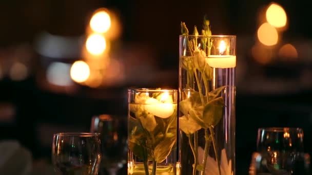 Hochzeitsbankettsaal Interieur Details mit dekorierten Tischen im Restaurant. Kerzen und weiße Blütenblätter mit Rosenblüten in mit Wasser gefüllten Glasvasen. — Stockvideo