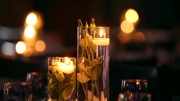 Bröllop bankett hall inredningsdetaljer med dukade bordet inställning på restaurang. Ljus och vita kronblad dekoration med rosor blommor i glasvaser fyllda med vatten. — Stockvideo