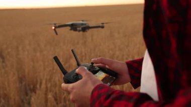 Çiftçi elleri elleri ile uzaktan kumanda tutarken quadcopter arka plan üzerinde uçuyor. Uçak uçar ziraat mühendisi buğday alanında uzak gelir. Tarım yeni teknolojiler ve yenilikler.