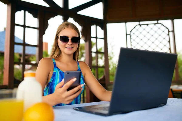 Freelancer woman sitting at garden house in tropical summer location and working with laptop remotely in swimsuit. Traveling Thailand with a computer and wi-fi internet. Telecommuting concept — Stock Photo, Image