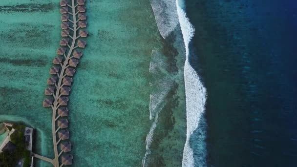 Vista aérea del complejo turístico de la isla tropical con bungalows y olas turquesas del océano Índico en Maldivas, vista desde arriba de las lujosas habitaciones de agua y surf, oleaje — Vídeo de stock