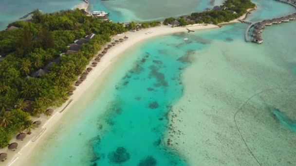 Luchtfoto van tropisch eiland resorthotel met witte zand palmbomen en turkooizen Indische Oceaan op Malediven, drone-beelden van bovenaf in 4k — Stockvideo