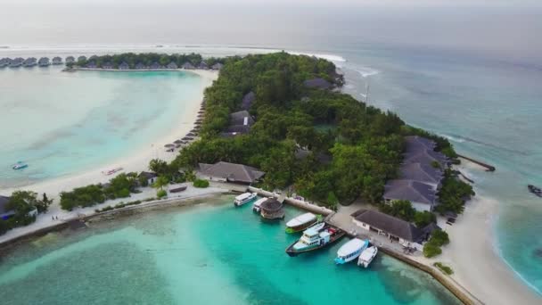 Luchtfoto van tropisch eiland resorthotel met witte zand palmbomen en turkooizen Indische Oceaan op de Malediven, dok, boten en ferries drone-beelden van bovenaf in 4k — Stockvideo