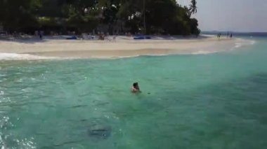 Hava dron kamera çift Hint Okyanusu üzerinde boş bir plaj yüzme etrafında sinekler. Banyo ve yukarıdaki mavi zümrüt Denizde öpüşme balayı iki lovers görüntüleri