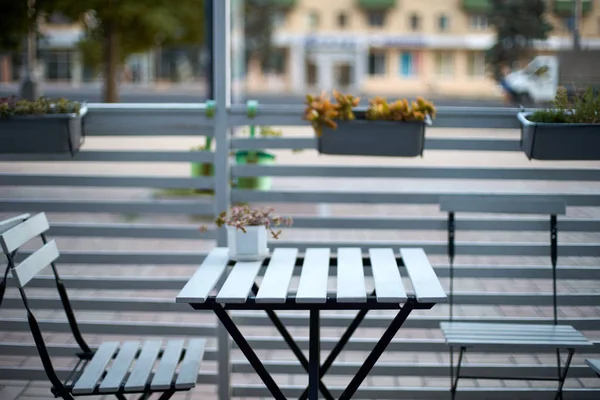 Mesa de tablones de madera blanca, sillas y valla horizontal de café en la calle. Fondo para la colocación del producto. Aislado al aire libre vacío europeo restaurante o cafetería exterior. No hay gente . —  Fotos de Stock