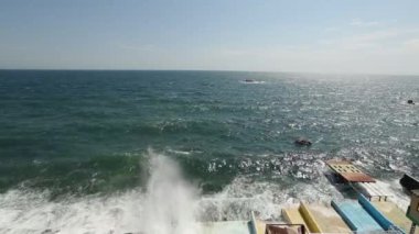 Büyük dalgalar hakkında waterfront sıçramasına ve cam gibi deniz suyu damla mavi gökyüzünde püskürtme set of breaking. Rüzgarlı bir gün denizde fırtına. Şişme tekne dalgalar kayalar. Sakinleştirici görüntüleri.