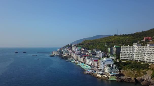 Drohnenaufnahmen von farbenfrohen Stadtlandschaften in den Bergen über dem Meer, Europa, dichten mehrstöckigen Gebäuden am Meer im Ferienort. Kamera steigt in den Himmel empor. Krim, Utellings, Schwarzes Meer. — Stockvideo