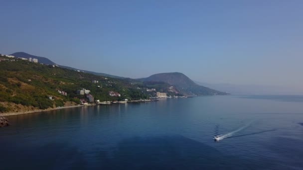 Filmato aereo con drone di un motoscafo che naviga in acque blu. Montagne e mare sullo sfondo. Il paesaggio europeo. La telecamera va avanti. Crimea, Utes, Mar Nero . — Video Stock