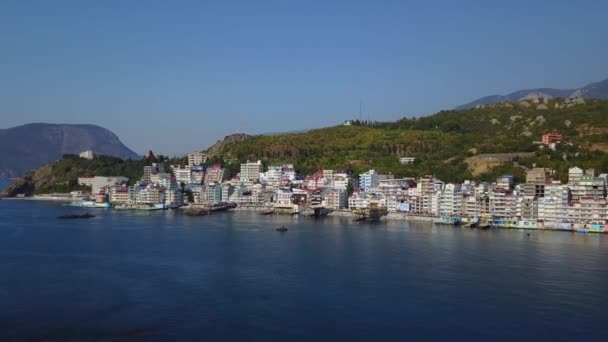 Antenn drönare utgående skott av färgglada stadsbilden i bergen över havet, Europa. Tät flera våningar byggnad vid havet i semesterorten. Kameran flyttas bakåt. Krim, Utes Ellings, Svarta havet. — Stockvideo