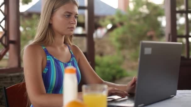 Freelancer woman sitting at garden house in tropical summer location and working with laptop remotely in swimsuit. Traveling tropics with a computer and wi-fi 4g 5g internet. Telecommuting concept — Stock Video