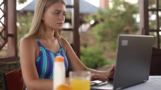 Mujer freelancer sentada en la casa del jardín en la ubicación tropical de verano y trabajando con el ordenador portátil a distancia en traje de baño. Viajar por los trópicos con un ordenador y wi-fi 4g 5g de Internet. Concepto de teletrabajo — Vídeos de Stock