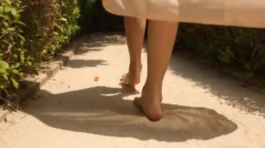 Arkadan görünüm kadının ayak exotical tropik adada spa Odalı Bungalov için gidiyor. Sarışın kız gülümseyerek yalınayak yakınındaki Maldivler avucunda beyaz kum yürür. Portrair görünüm