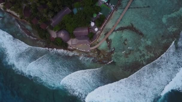 Widok z góry Wyspy Malediwy, cameragoes w dół do baru hotelu tropical luxury resort. Drone malejącej nad restraunt Wyświetlono surf ogromne i duże fale z góry. Antena fooage znaki kaligraficzne — Wideo stockowe