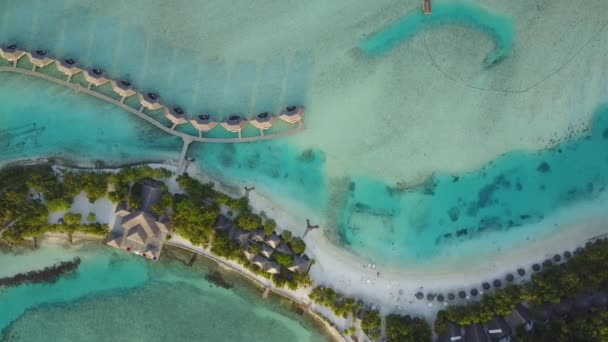 Hava dron kamera ile beyaz kum plaj tropikal ada ve palmiye ağaçları gölgeler, bungalovlar ve turkuaz Hint Okyanusu üzerinde Maldivler tesisi ile döner — Stok video