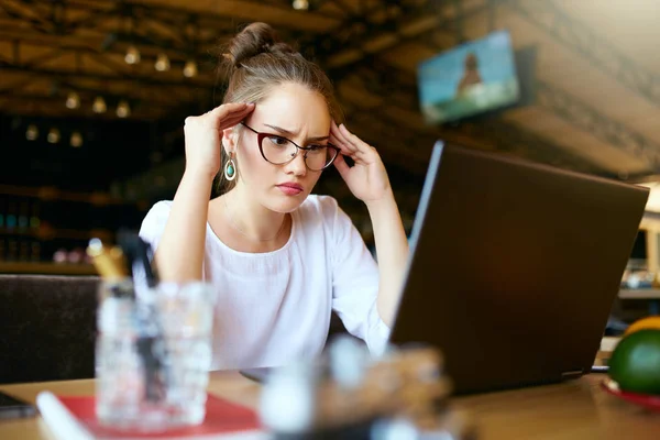 Young stressed asian freelancer massaging temples to reduce headache, noisy workspace giving migraine, relieving stress, chronic pain. Mixed race designer woman sitting in front of laptop at office. — Stock Photo, Image