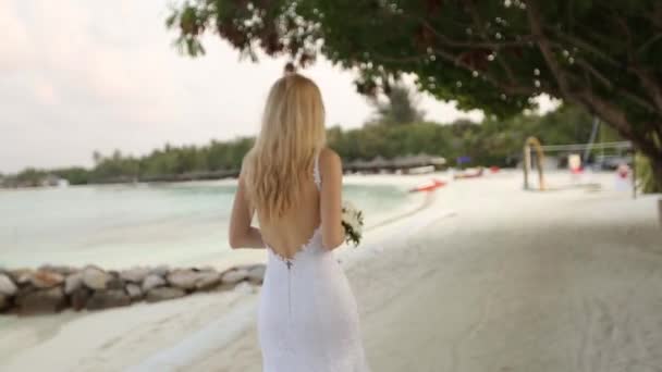 First look of young wedding couple. Bride goes to wedding ceremony on romantic tropical island on the white sand beach near azure lagoon ocean on Maldives