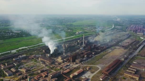 Luchtfoto uitzicht over geïndustrialiseerde stad met sfeer en rivier water veroorzaakte luchtverontreiniging metallurgische fabriek in de buurt van de zee. Vieze rook en smog uit buizen van staal fabriek en hoogovens. Ecologische — Stockvideo