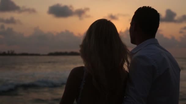 Back view of bride and groom enjoying sunset on tropical beach near balustrade on vacation. Newlyweds hugging and watching ocean after ceremony on honeymoon. Tropical wedding at Maldives luxury spa — Stock Video