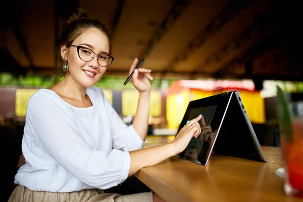 Digital artist finger touches convertible to 2 in 1 laptop display in tent mode and holds stylus. Mixed race multiethnic asian caucasian woman working on project design, writing notes on touchscreen. — Stock Photo, Image