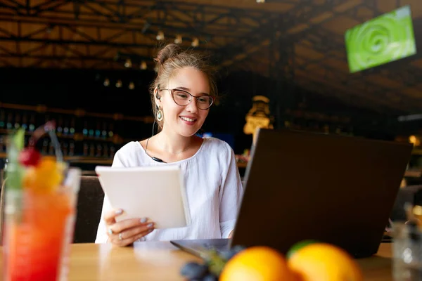 Businesswoman working remotely at cafe with headset and laptop. Mixed race female performing business negotiations on video chat. Telecommuting concept. Freelancer speaking on cellphone via headset. — Stock Photo, Image