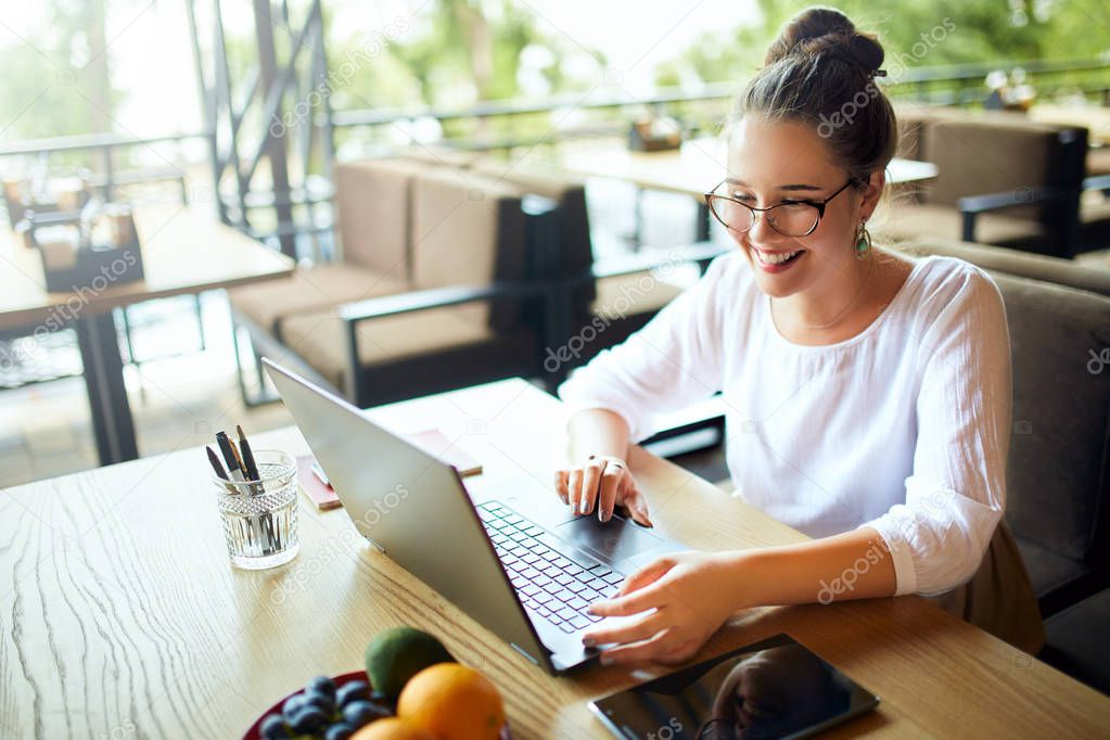Young mixed race woman working with laptop in cafe at tropical location. Asian caucasian female studying using internet. Business woman doing social marketing work and shopping. Telecommuting concept.