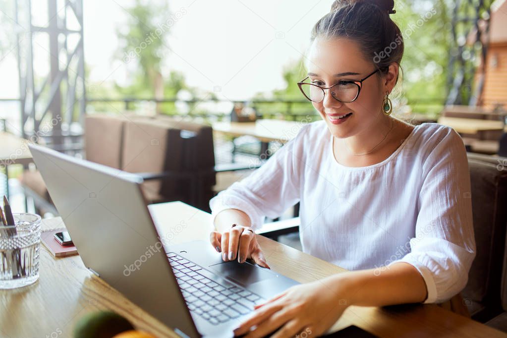 Young mixed race woman working with laptop in cafe at tropical location. Asian caucasian female studying using internet. Business woman doing social marketing work and shopping. Telecommuting concept.
