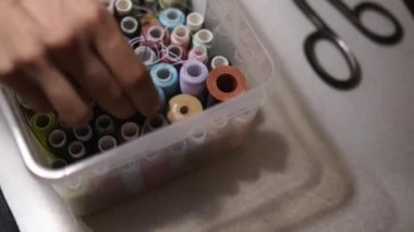 Kutu dikiş ipliği makaraları. Moda Tasarımcısı adam el Organizer'da farklı renkli konuları tam kazma. Terzi atölyesi çalışıyor. İğne işi için doğru renk iplik Aradığınız terzi.