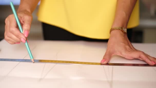 Vue rapprochée des mains de créatrice de mode travaillant en studio. Tailleur féminin caucasien dessin de la disposition des vêtements sur tissu à l'aide d'un crayon et une règle. Atelier intérieur . — Video