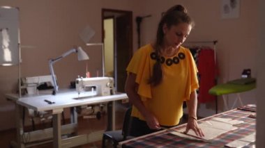 Stüdyoda çalışan kadın moda tasarımcısı. Beyaz kadın terzi kıyafet için Düzen tebeşir ve cetvel kullanarak kumaş üzerinde çizim. Atelier kapalı.