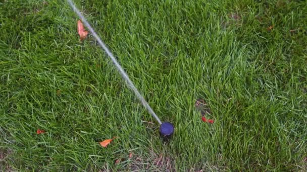 Garden irrigation sprinkler watering lawn in the park near walkway. Automated rotating irrigation system. Green grass and landscape design. Camera on slider, tracking shot in 4k. — Stock Video