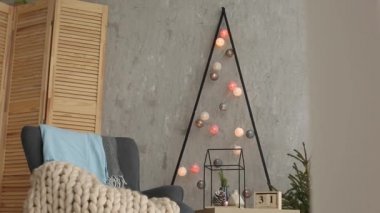 Bir şık koltuk ve sıcak merinos ekose ile şık Noel İskandinav iç. Konfor nordic Yılbaşı dekor ile ev. Çelenk ve ışıklar ile minimalist Noel ağacı.