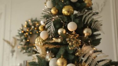 Şık beyaz Noel iç süslü çam ağaçları ile. Konfor ev Noel ağacı altın süslemeleri dolu, çelenk ve arka plan üzerinde çelenk ışıkları ile. Yeni yıl arifesinde.