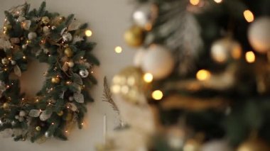 Şık beyaz iç fir Noel ağaçları ve çelenk altın süslemeleri, oyuncaklar, ışıklar ve çelenk dolu. Çelenk arka plan üzerinde. Yeni yıl arifesinde evde.