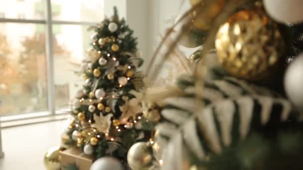 Elegante interno bianco di Natale con abeti decorati, camino, lanterne, lampade, candele, ghirlanda, dossi e regali. Casa comfort con albero di Natale pieno di decorazioni dorate, luci e — Video Stock