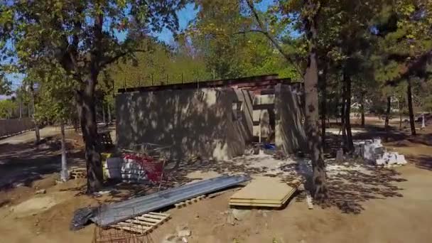 Légi felvétel épület építési telek, az erdő egyetlen cocrete. Kamera repül felé a ház és az építőanyagok. Quadcopter drone repül el vakolt WC-park. — Stock videók