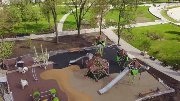 Images aériennes d'une aire de jeux pour enfants de luxe dans un parc de banlieue. Reconstruction du parc pour les enfants. Les travailleurs posant de la miette de caoutchouc coloré sur le sol. Travaux de construction . — Video