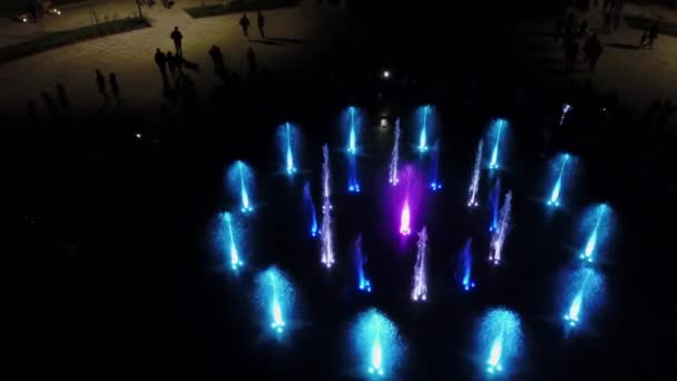 Luftaufnahmen von tanzenden bunten Springbrunnen in der Nacht. farbige Wasserstrahlen, die im Dunkeln mit Lampen beleuchtet werden. — Stockvideo