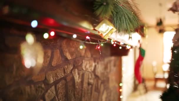 Mannen i kniited tröja hängande Christmas Krans ovan sten autentiska spis dekorerad med färgglada blinkande garland lampor. Nya året semester förberedelser och dekoration. Nära Visa dolly skott. — Stockvideo