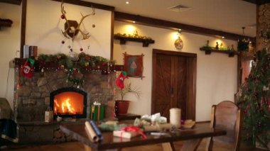 Yangın yanık içinde bir şömine Noel arifesinde garland ışıklar, çelenk, çorap ve hediyeler ile dekore edilmiştir. Hediyeler ve ambalaj malzemeleri: kağıt, köknar ağacı dalları, koni ve kurdeleler masada kaydırma.