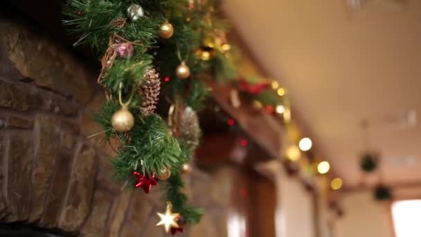 Hombre barbudo en suéter con cuchillos y sombrero colgando de la media de Navidad o calcetín por encima de la chimenea decorada con luces de guirnalda intermitentes de colores y corona. Año Nuevo vacaciones preparación y decoración . — Vídeos de Stock
